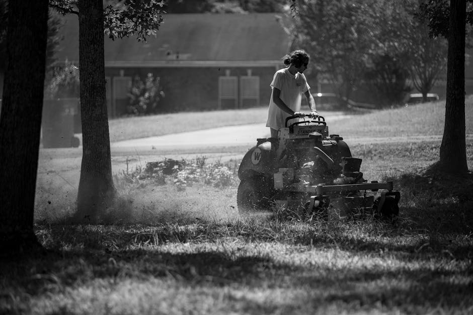 Pushing lawn mower across green grass